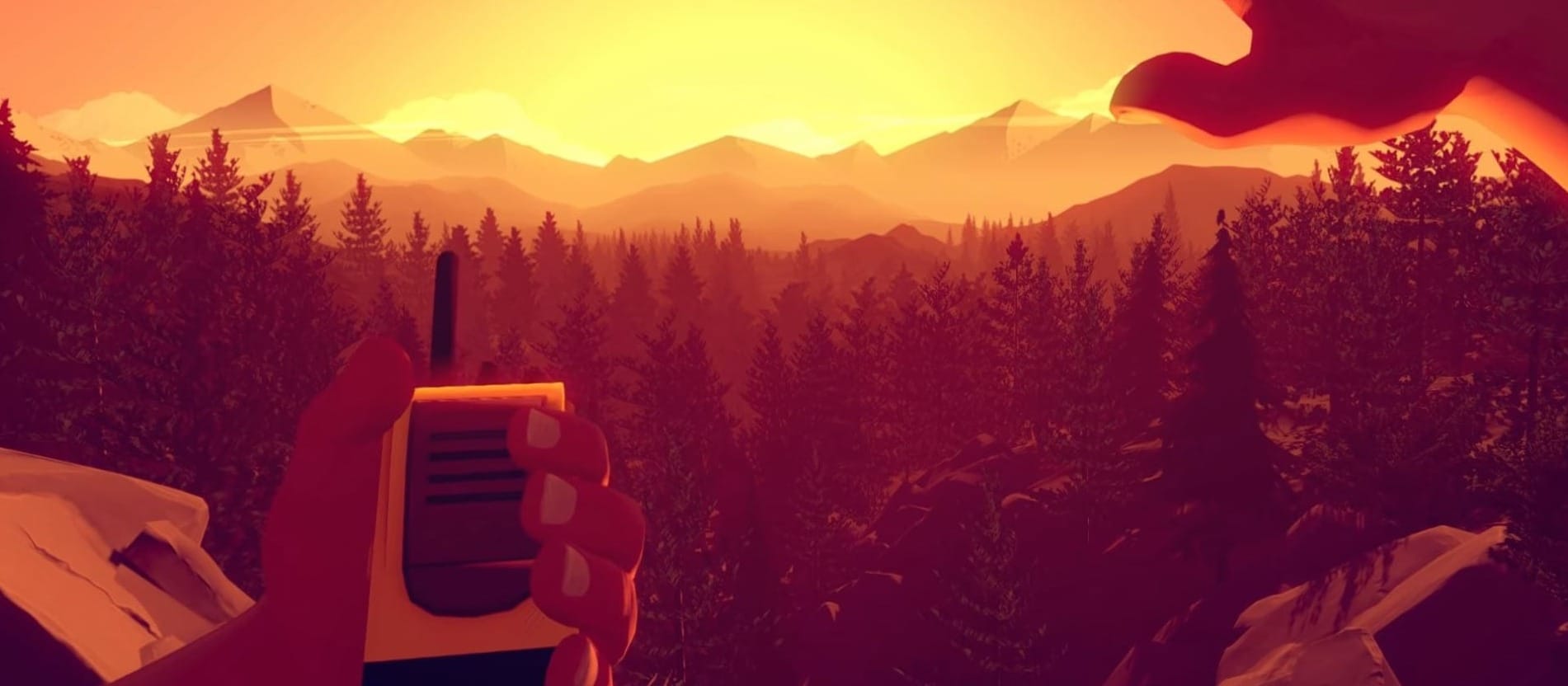 A screenshot from the Firewatch game, with the main chatacter from the first person view talks to the hand radio and covers his eyes with a hand looking at beautiful sunset in the mountain horizon.